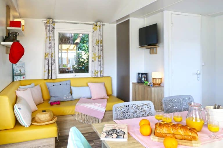 Salon lumineux avec canapé jaune et petit-déjeuner servi.