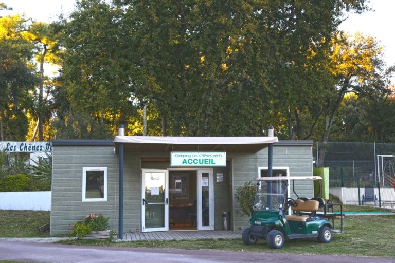 Entrée accueil du camping sous les arbres verts.
